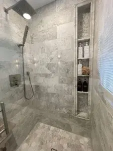 Remodeled bathroom with walk in shower featuring modern tile and built in storage.